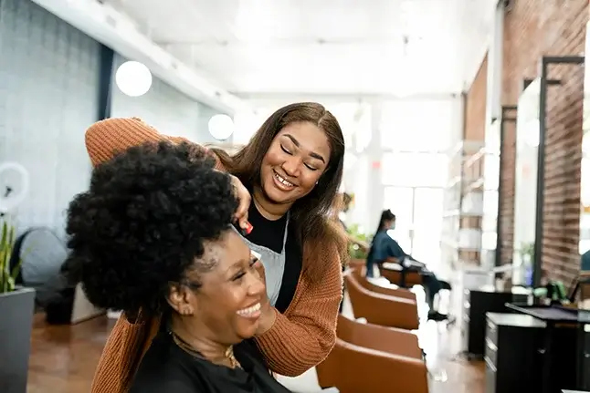 A hairstylist trimming a customers hair in a beautify salon.
