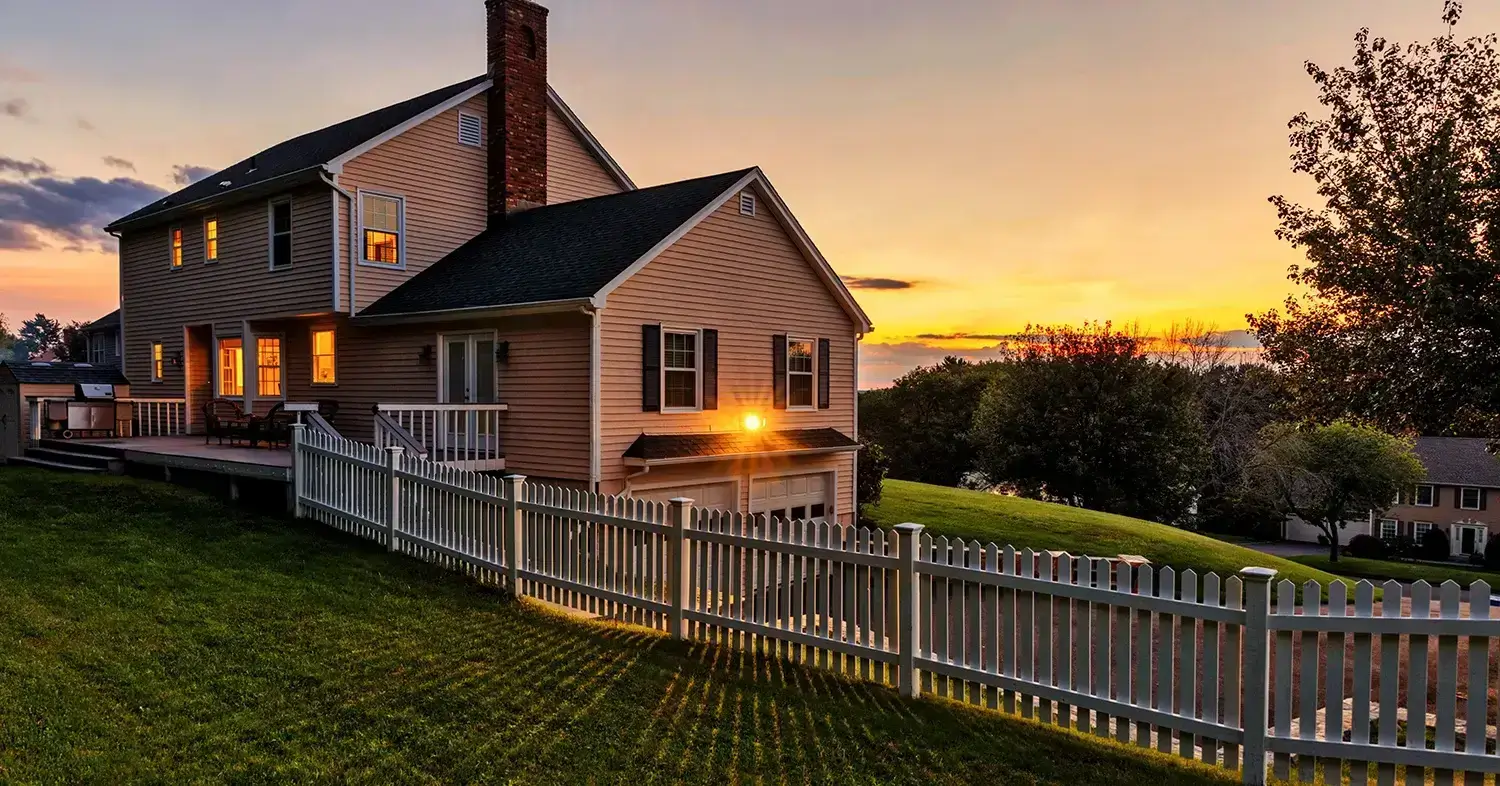 A house with a white fence and a sunset reflection.